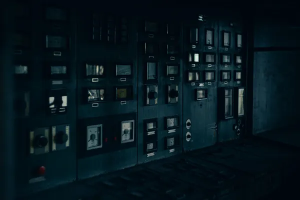 Industrial control panel gauges in a darkened facility