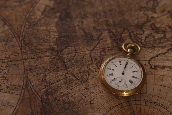 A gold pocket watch resting on an antique world map, the navigation problem GPS solved by hiding the clock in orbit.